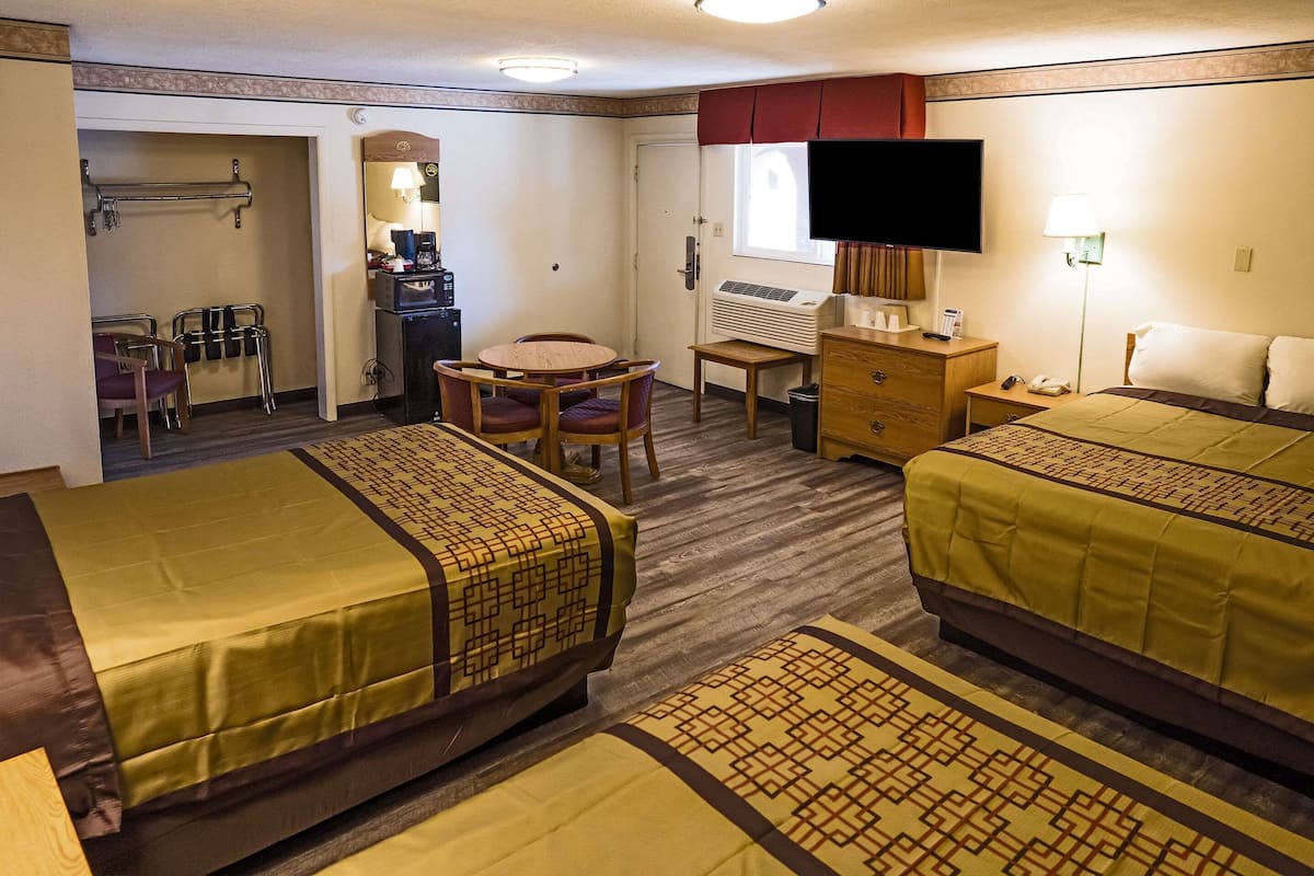 A hotel room with two beds, a desk, a chair, a television, and a window.