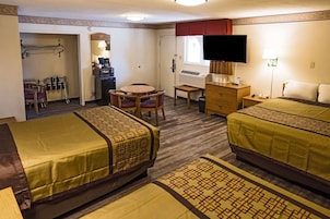 Habitación de hotel con dos camas, un escritorio, una silla, un televisor y una ventana.