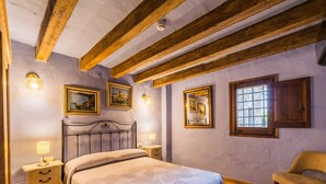 Una camera da letto con un letto, comodini, una sedia e quadri appesi alle pareti.