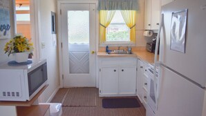 A compact kitchen with white cabinets, a microwave, a refrigerator, and a sink.