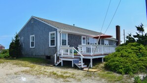 A two-story house with a porch, a chimney, and a sign indicating it is for sale.