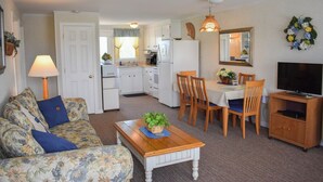 A compact living space with a sofa, dining table, chairs, a television, and a kitchen area.