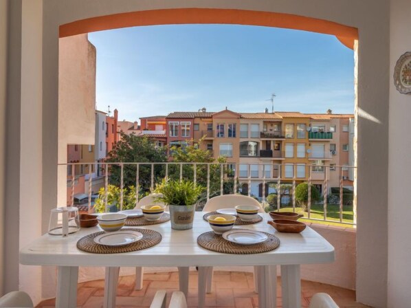 Un balcon avec une table dressée pour le dîner, donnant sur une rangée de bâtiments aux couleurs vives.