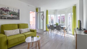 Un soggiorno moderno con un divano verde, un piccolo tavolo bianco e un'area pranzo con sedie e tavolo.