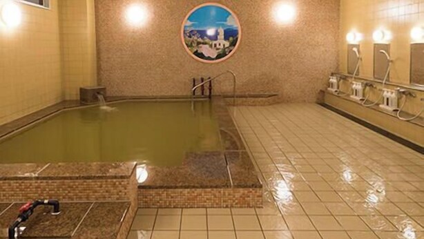A large indoor swimming pool with a tiled floor and a wall-mounted circular artwork depicting a night scene.