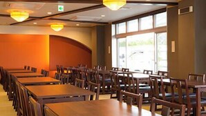 A large dining area with multiple wooden tables and chairs, arranged in rows.