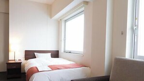 A hotel room with a bed, a nightstand, a chair, and a window.