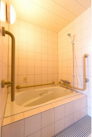 A modern bathroom with a bathtub, a shower, and grab bars. - Hotel Topaz Ozai Ekimae (Oita)