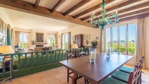 Un comedor con mesa y sillas de madera, un banco verde y una araña.