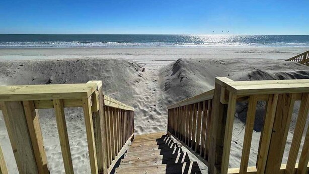 A wooden boardwalk leading to a beach with sand dunes and a clear blue sky. - Family Seaclusion - Oceanfront in Garden City Beach (Garden City Beach)