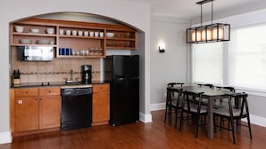 A kitchen with wooden cabinets, a black refrigerator, and a dining table with chairs.