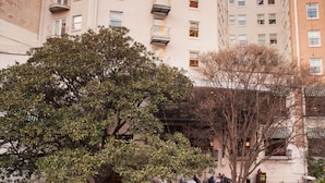 A multi-story building with balconies, a courtyard with tables and chairs, and a pond with ducks.