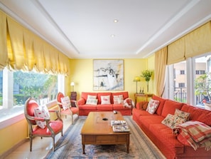 Sala de estar com sofá vermelho, mesa de centro de madeira e uma grande pintura abstrata na parede.