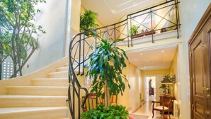 A staircase with a metal railing, a potted plant, and a wooden floor.