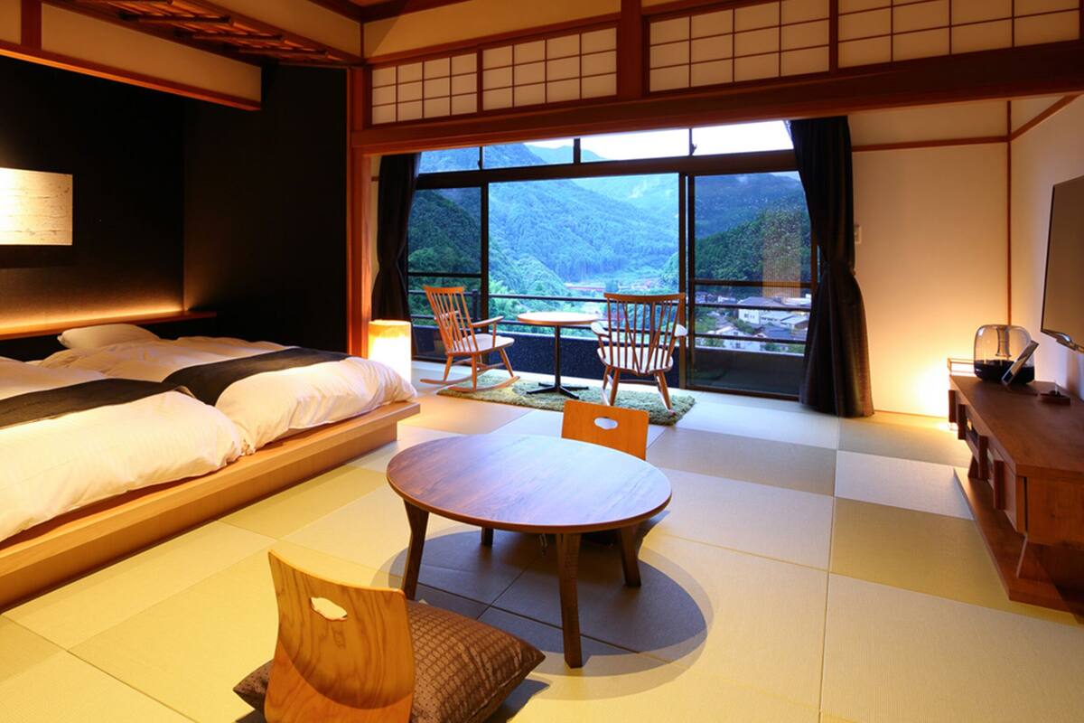 A traditional Japanese-style bedroom with a large bed, a small table, and chairs.