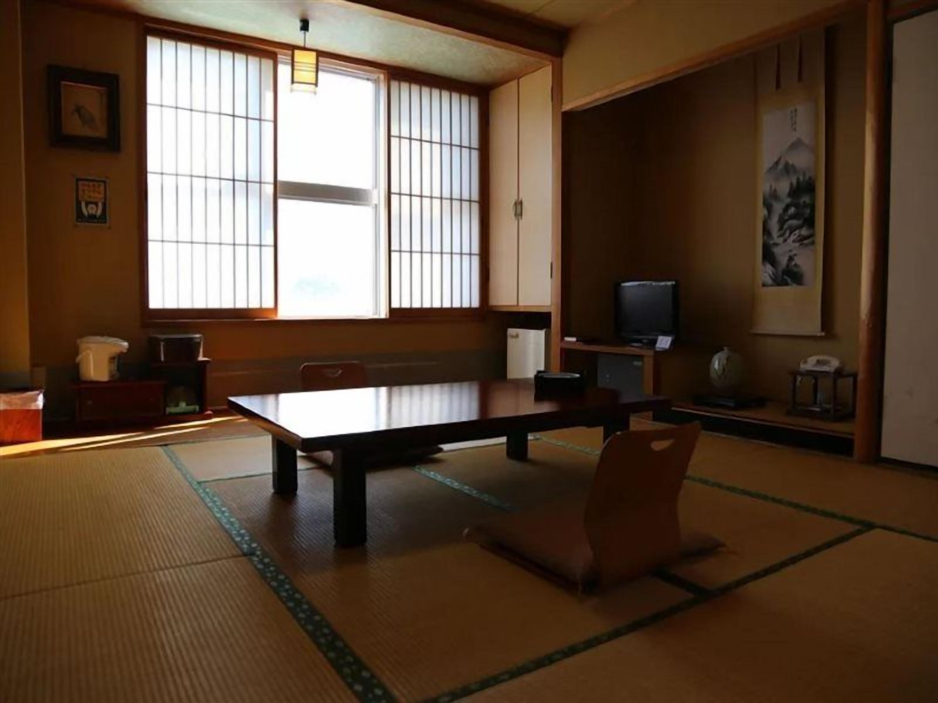A traditional Japanese room with tatami flooring, a low table, and a television.
