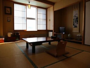 A traditional Japanese room with tatami flooring, a low table, and a television. - Tara Kanko Hotel (Tara)