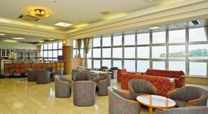 Un espacio interior amplio con diversas disposiciones de asientos, una zona de bar y ventanas grandes que ofrecen vistas al exterior.