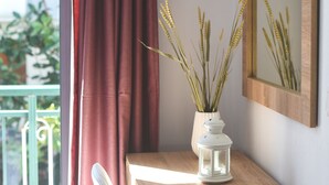 A wooden desk with a white vase containing dried plants, a white lantern, and a mirror on the wall. - Albertos House (Skiathos)