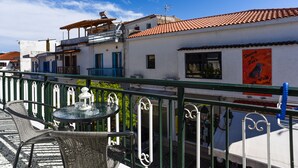 A terrace with outdoor seating, a view of the street, and a building with a sign for "Danny & Zoo's". - Albertos House (Skiathos)