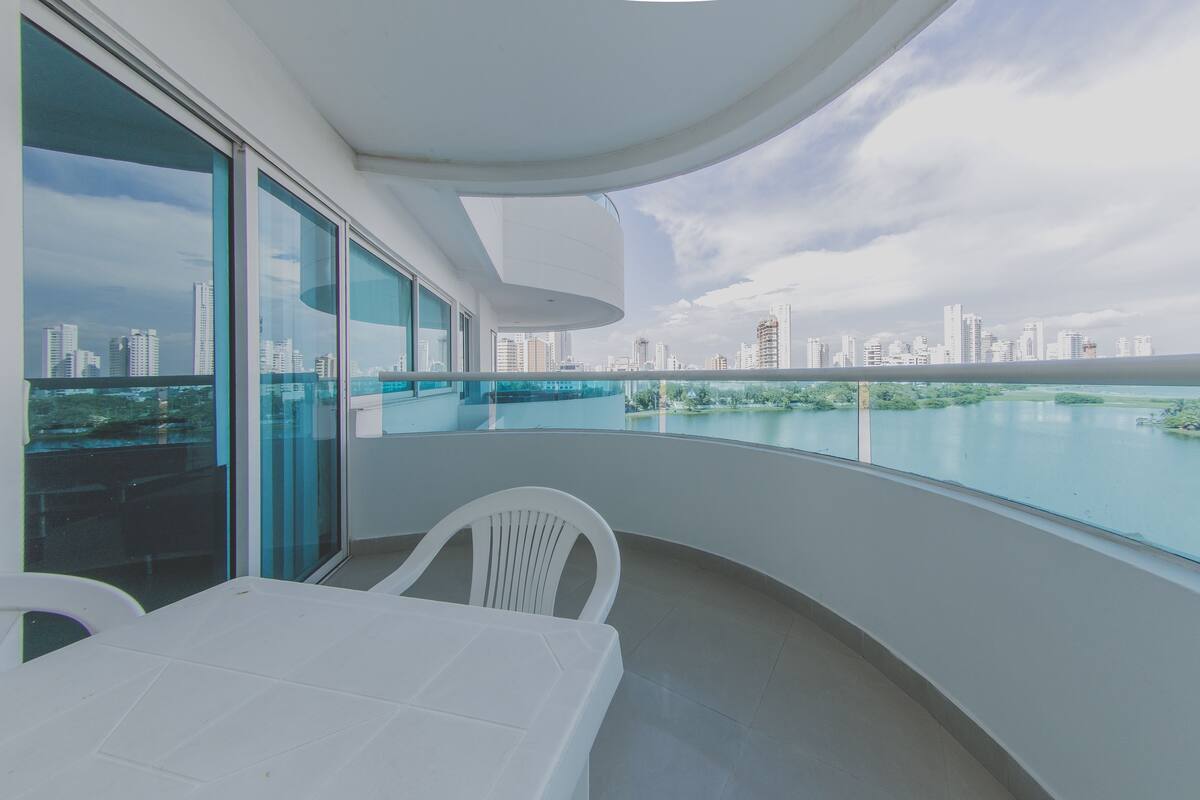 A modern balcony with a city view, a white table, and a chair.