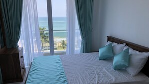 Une chambre à coucher avec un lit, des rideaux et une vue sur l’océan.