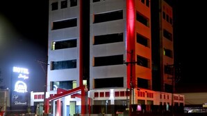 Un hôtel à plusieurs étages, doté d’une façade rouge et blanche bien visible, d’une entrée facilement identifiable et d’une enseigne indiquant qu’il s’agit d’un hôtel et d’un restaurant.