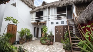 Un patio con un edificio de techo de paja, plantas en macetas y un diseño decorativo en el suelo.
