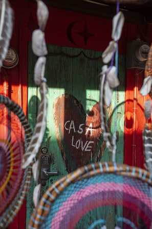 A room with a rustic wooden door, a heart-shaped window, and a wall with graffiti. - CasaLove (La Cruz de Huanacaxtle)