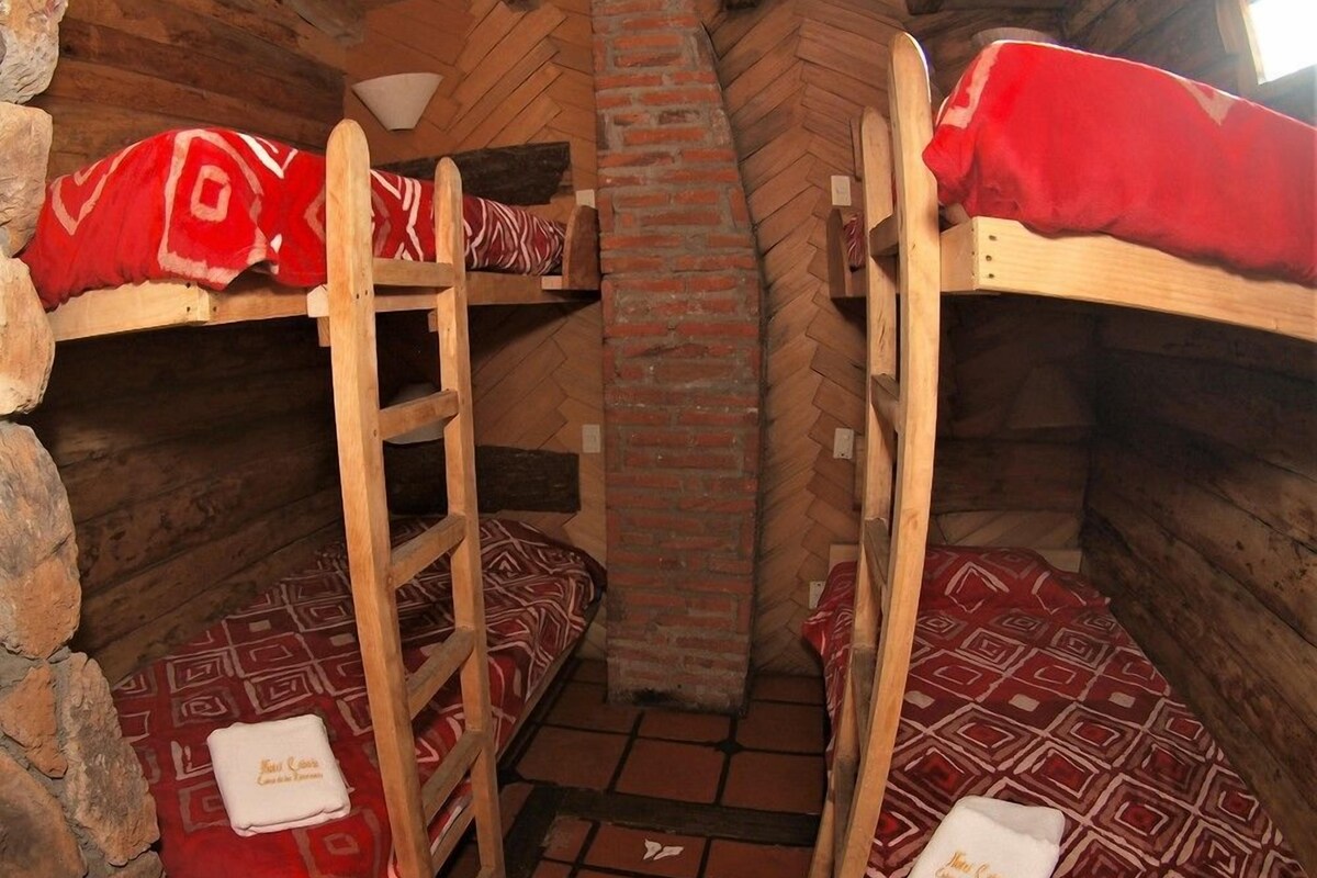 Una habitación con literas, una chimenea de ladrillo y una escalera.