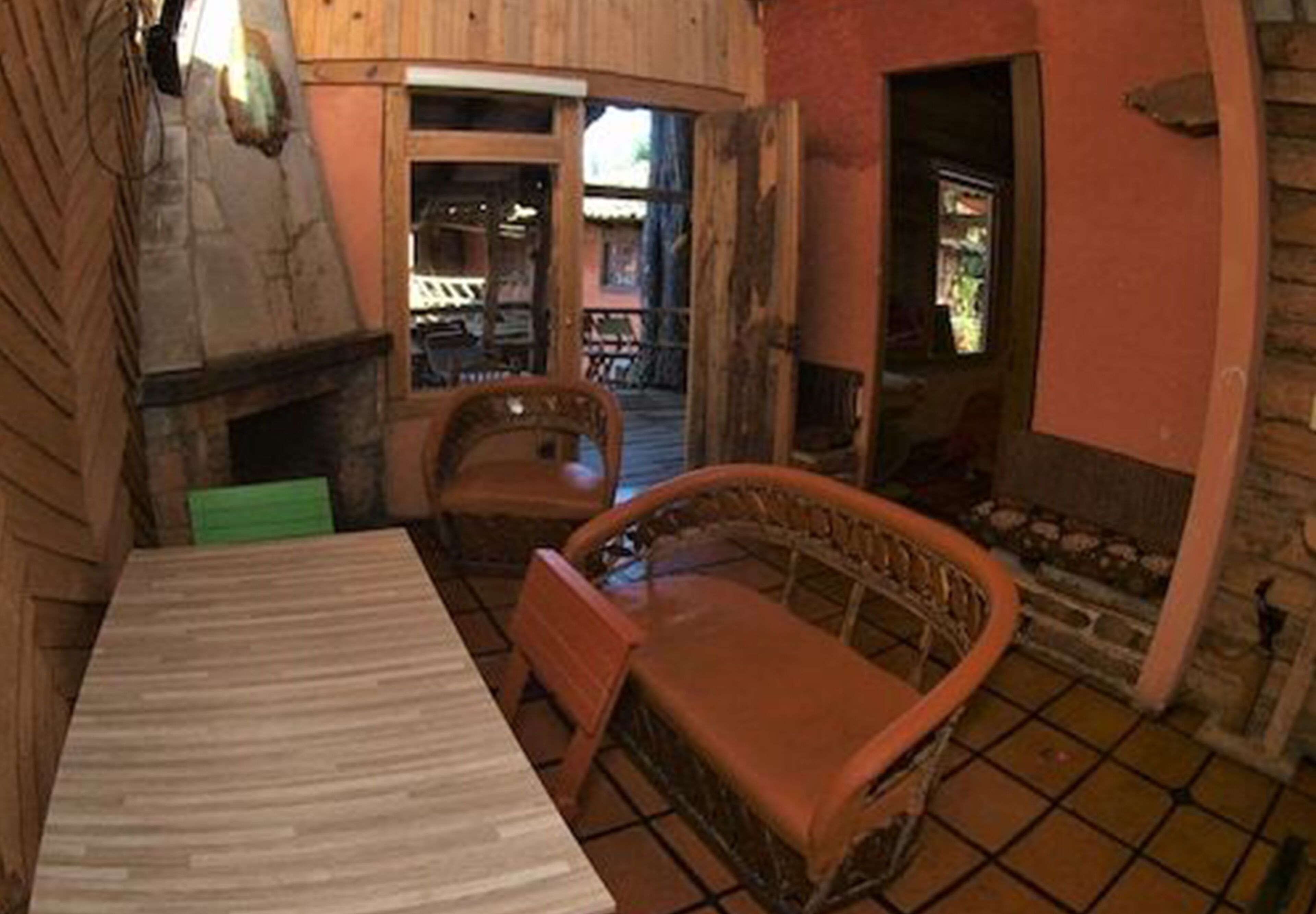 A rustic room with a wooden table, wicker chairs, and a stone fireplace.