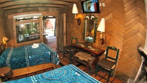 Una habitación con dos camas, un escritorio de madera, una silla, un espejo y un televisor.