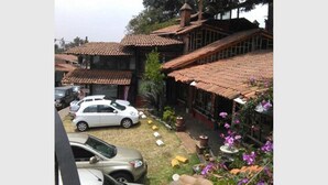 Un edificio tradicional con tejado de baldosas y un jardín lleno de flores y plantas.