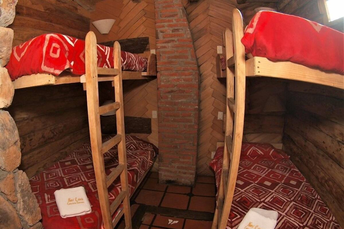 Une pièce avec des lits superposés, une cheminée en briques et une échelle.