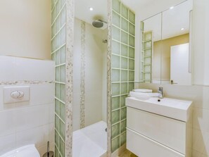A modern bathroom with a glass shower enclosure, a white sink, and a mirror above it. - Les Patios by Interhome (Saint-Tropez)