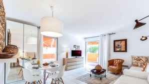 Un salon moderne comprenant un coin repas, un téléviseur et une grande fenêtre.