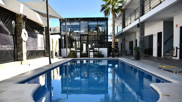 Une piscine dotée d’une conception architecturale moderne, avec des parois en verre et un bord en béton.