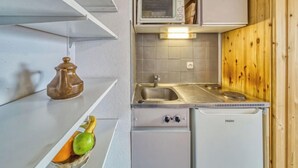 Une cuisine compacte équipée d’un four à micro-ondes, d’un évier et d’un petit réfrigérateur.