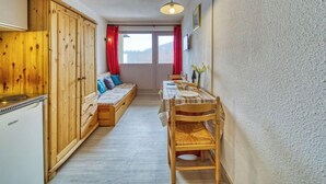 Une pièce de taille modeste, comprenant une armoire en bois, un canapé, une table à manger avec des chaises et une petite kitchenette.