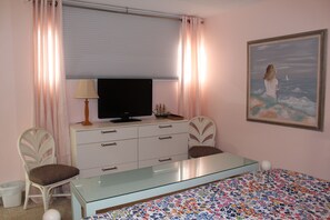 A bedroom with a bed, a TV on a dresser, a chair, and a painting on the wall. - Ocean View from the Balcony! (Rehoboth Beach)