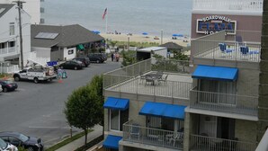 A building with a sign for Boardwalk Plaza, a parking area, and a view of the beach. - Ocean View from the Balcony! (Rehoboth Beach)