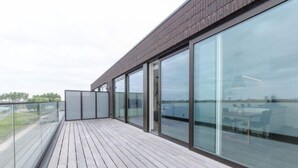 A modern building with large glass windows and a wooden deck.