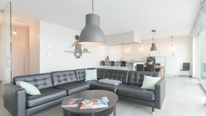 A modern living room with a sectional sofa, a coffee table, and pendant lighting.