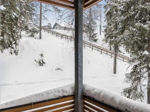 A snowy outdoor area with a wooden deck, snow-covered trees, and a metal railing. - Karhunvartijan linna a3 by Interhome (Kuusamo)