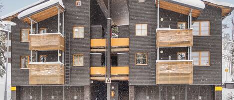A multi-story building with a symmetrical facade, wooden balconies, and a central entrance.