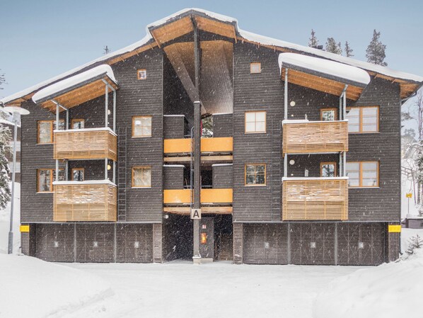 A multi-story building with a symmetrical facade, wooden balconies, and a central entrance. - Karhunvartijan linna a3 by Interhome (Kuusamo)