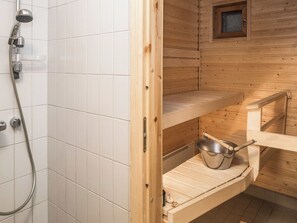 A wooden sauna with a shower area and a shelf with a metal basin. - Karhunvartijan linna a3 by Interhome (Kuusamo)