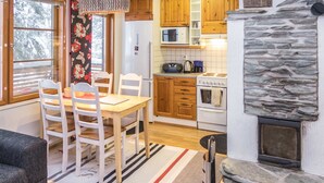 Una cocina acogedora con armarios de madera, una chimenea de piedra y un comedor con alfombra a rayas.