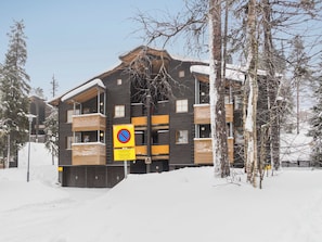 A multi-story building with a snow-covered roof and a no parking sign.
