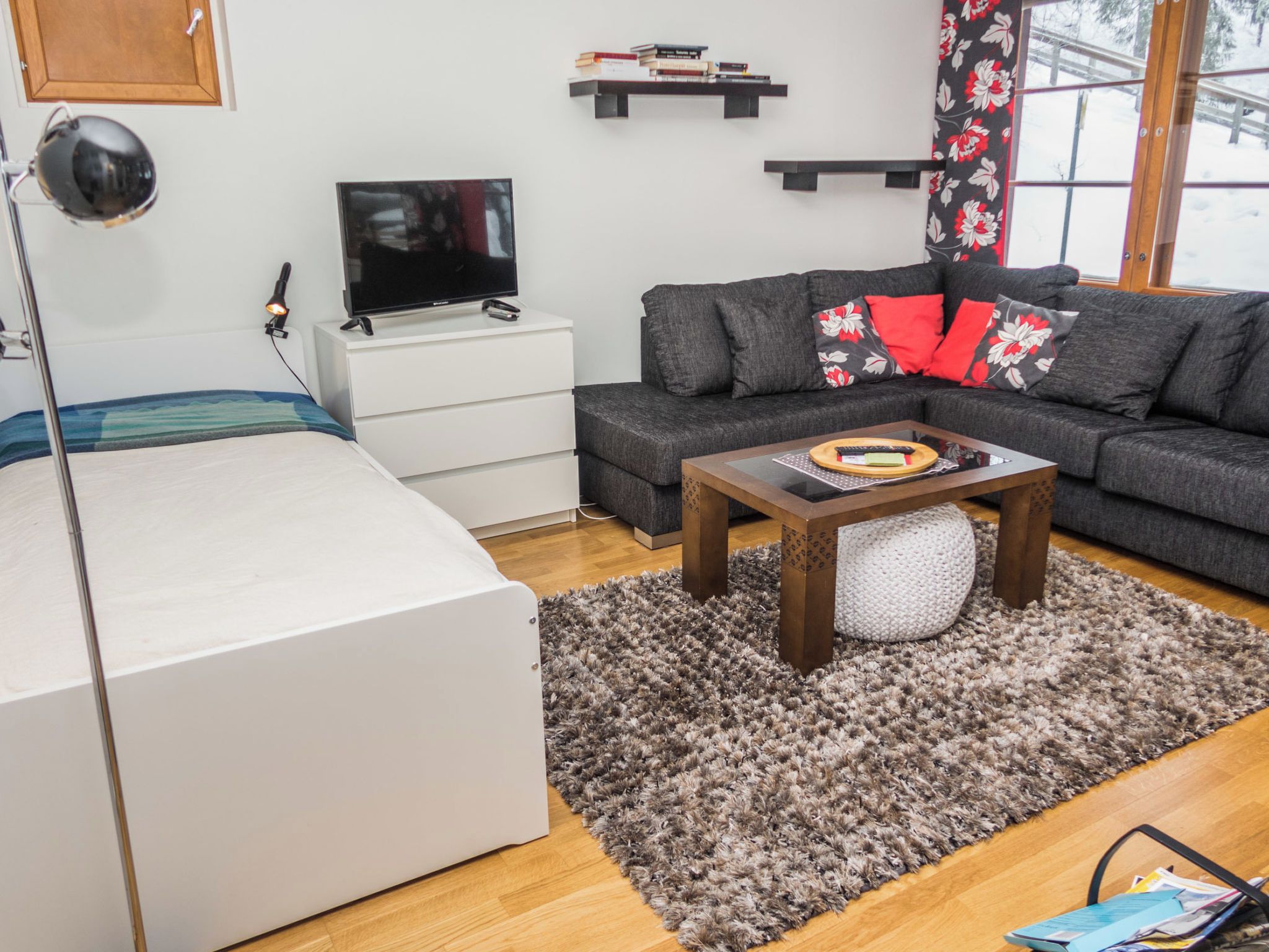 Un salon moderne comprenant un canapé, un téléviseur à écran plat, une table basse et un lit.